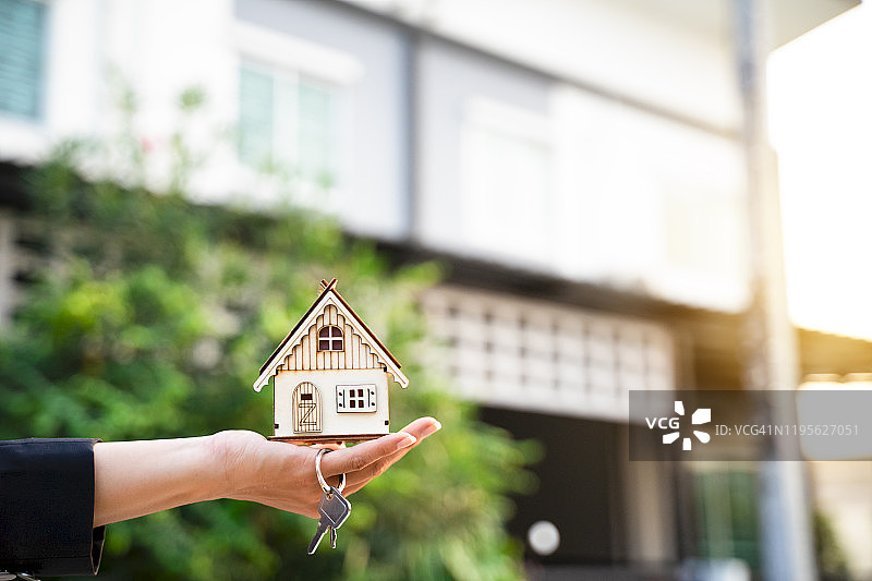 房地产经纪人展示房屋模型和钥匙：房屋买卖概念图片素材