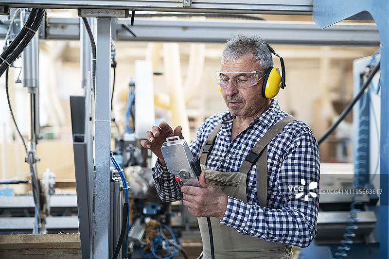 成年男人在工厂操作机器人图片素材