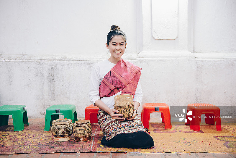 年轻亚洲女性在老挝琅勃拉邦街头等待向僧侣布施图片素材