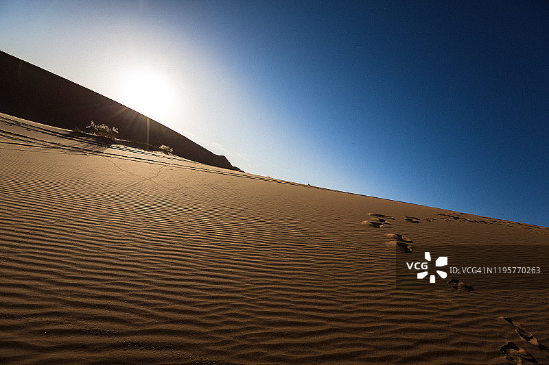 蓝色天空下的沙丘波浪图案图片素材