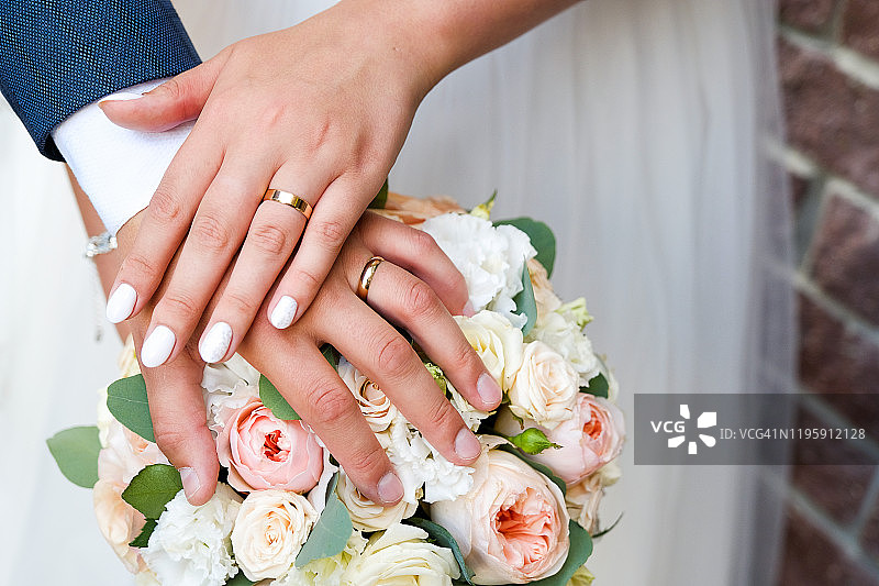 新娘和新郎在婚礼花束上的手图片素材