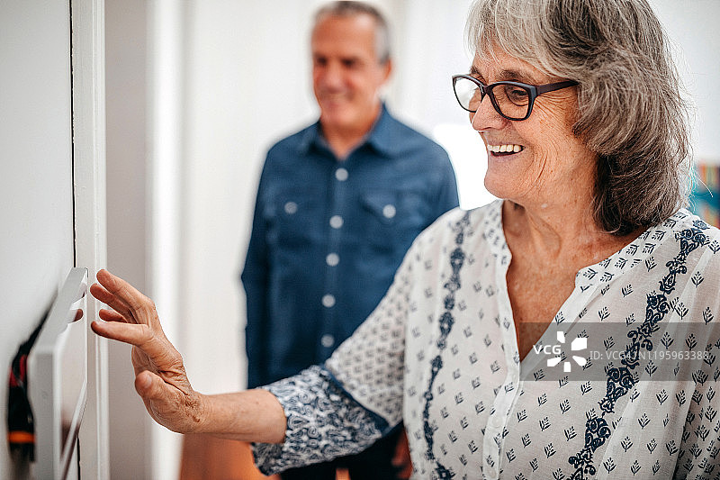 在疗养院中使用家庭自动化触摸屏面板的年长女性图片素材