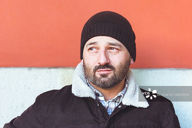 戴着羊毛帽靠墙的胡子男肖像图片素材