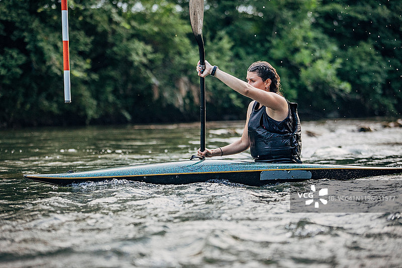 在河中训练的强壮女子皮划艇运动员图片素材