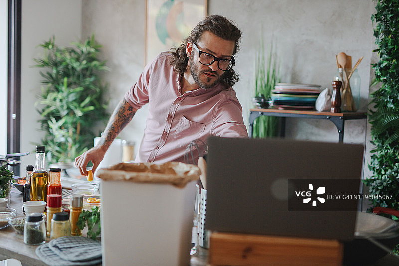年轻男人使用笔记本电脑查看烹饪食谱图片素材