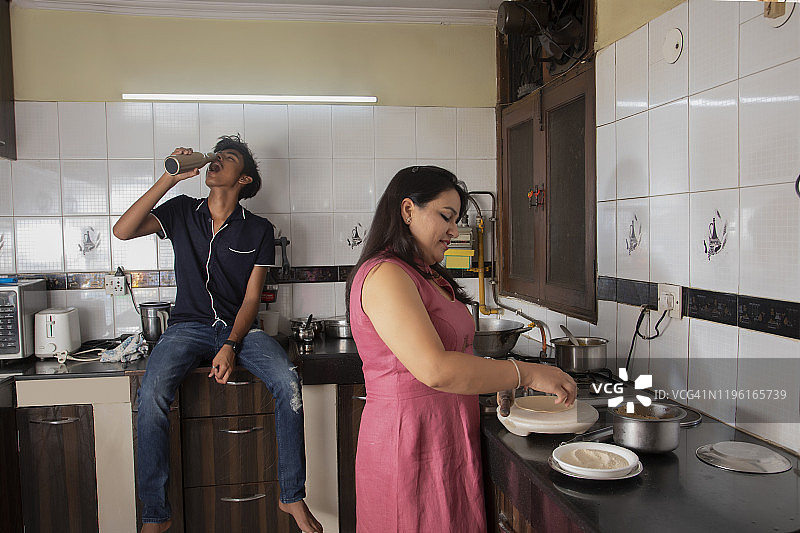 母亲在家做饭，儿子喝水图片素材