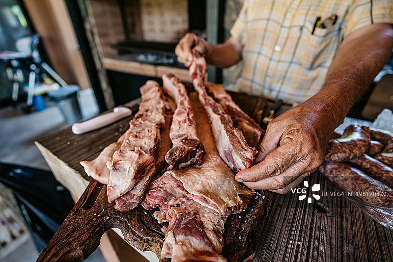 中年男人准备调味生肉做阿萨多烤肉图片素材