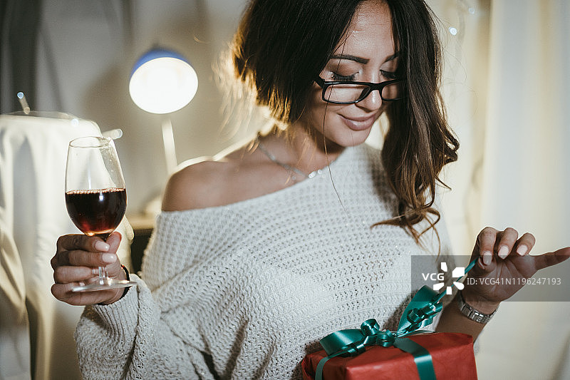 女人一边喝红酒一边包圣诞礼物图片素材