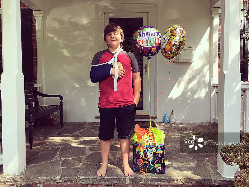 手臂骨折的小男孩和气球图片素材