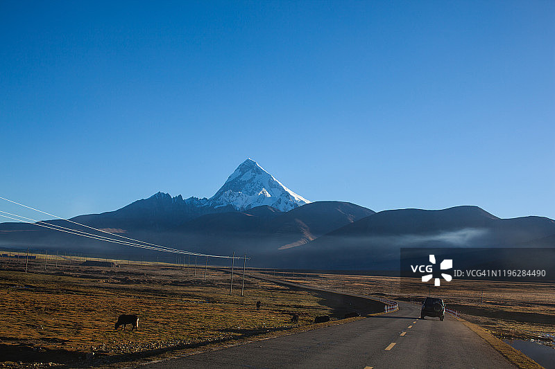 在通往雪山的公路上行驶的SUV图片素材