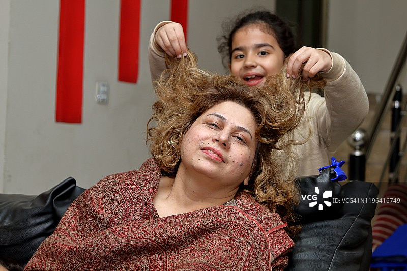 女儿玩耍并缠绕着妈妈的头发图片素材