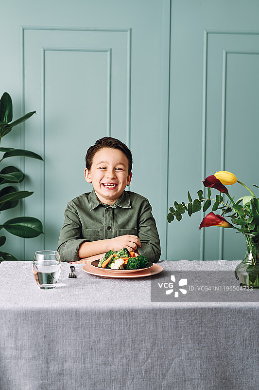 儿童非常高兴地吃蔬菜，盘子里有很多蔬菜，他喜欢蔬菜图片素材