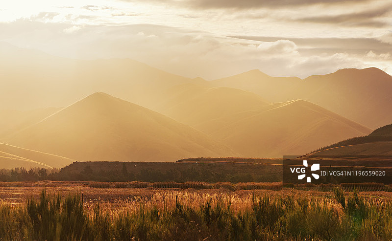 日落时分，蒂阿瑙和皇后镇之间的金色山丘上雾蒙蒙的光线，新西兰南岛图片素材
