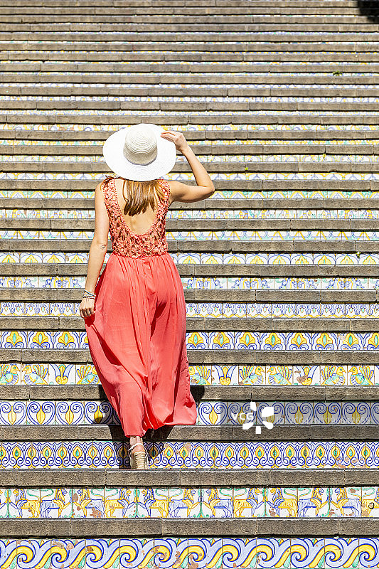 年轻女子在意大利西西里卡尔塔吉罗内的瓷砖楼梯上行走图片素材