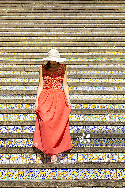 年轻女子走下意大利西西里卡塔尼亚省卡尔塔吉龙的瓷砖楼梯图片素材