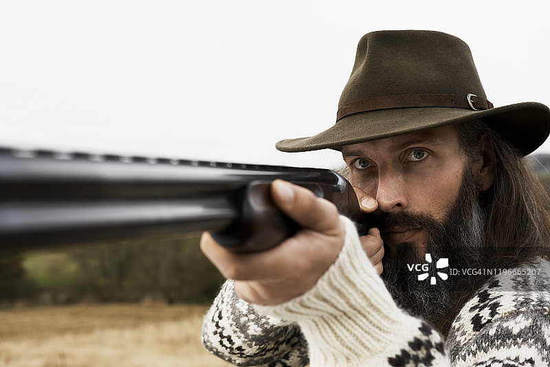 戴帽子的男人用猎枪瞄准的特写图片素材