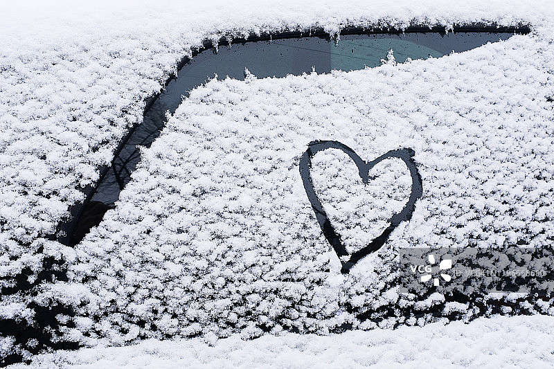 车玻璃上画着的心，以雪为背景。爱、浪漫、情人节的象征。图片素材