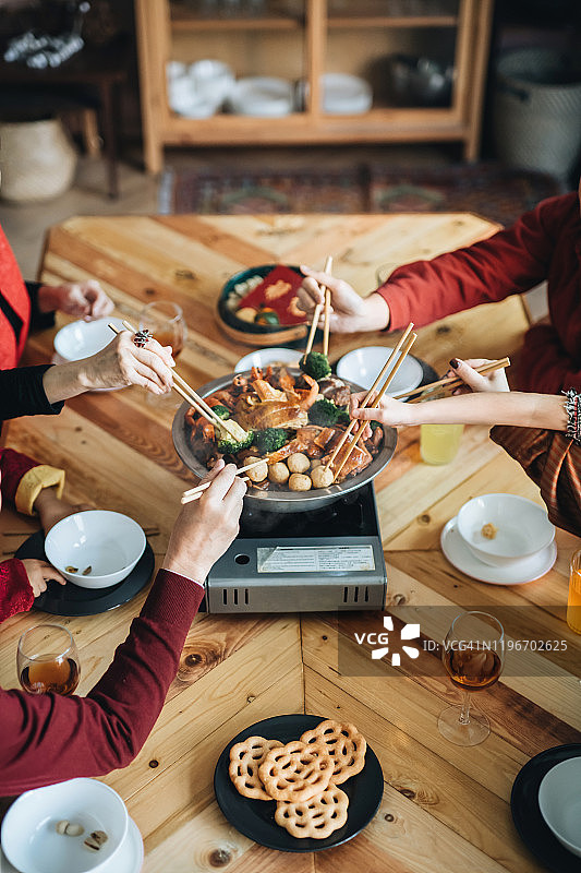 喜庆的亚洲家庭欢度中国新年，团圆饭享用美味的传统盆菜图片素材