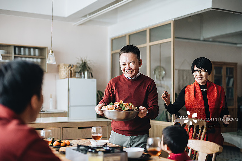 快乐的亚洲家庭庆祝中国新年，祖父母在团圆饭上提供传统中国盆菜图片素材