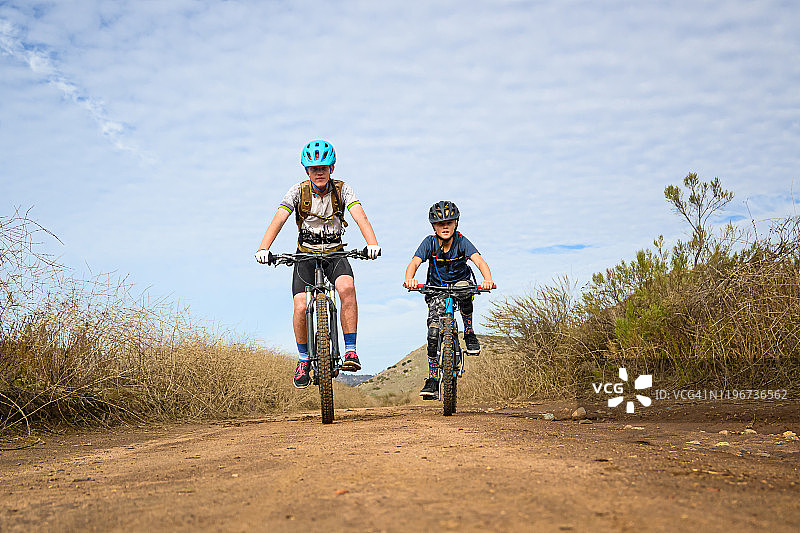 孩子们在仙人掌丛中骑山地自行车图片素材