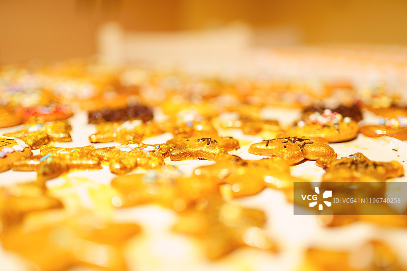 厨房桌子上装饰着金色和彩色装饰的迷你甜蛋糕，星形圣诞饼干图片素材