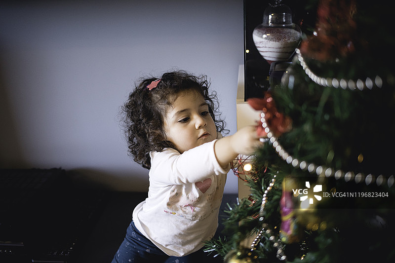 快乐的小女孩装饰圣诞树图片素材