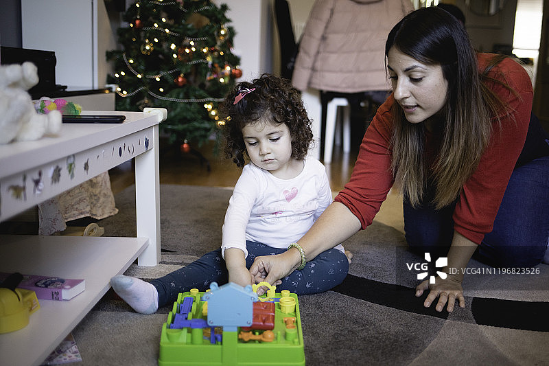 小女孩和妈妈在地板上玩圣诞新玩具图片素材