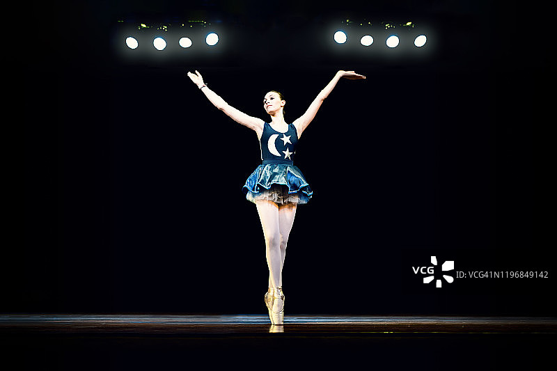 年轻女孩在黑暗的舞台上跳芭蕾舞图片素材