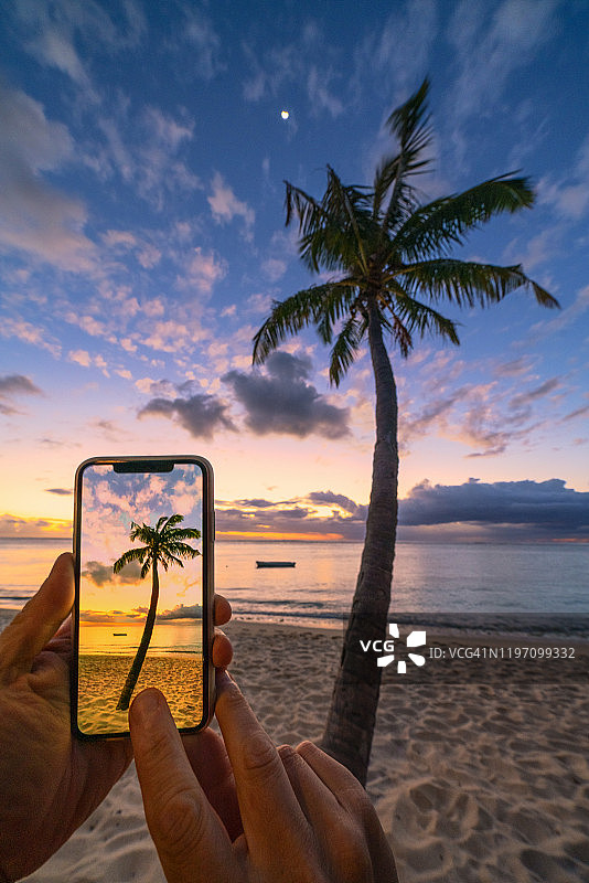 男子在毛里求斯岛用智能手机拍摄日落图片素材