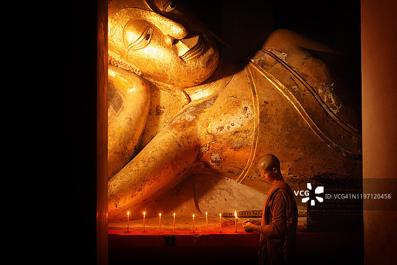 僧侣在寺庙中点燃蜡烛，祈祷佛像图片素材