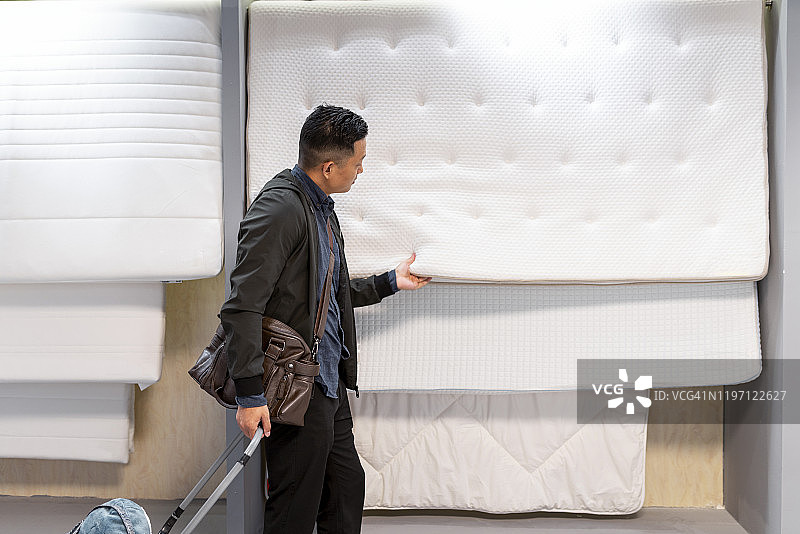 亚洲男子购物时选择床垫图片素材
