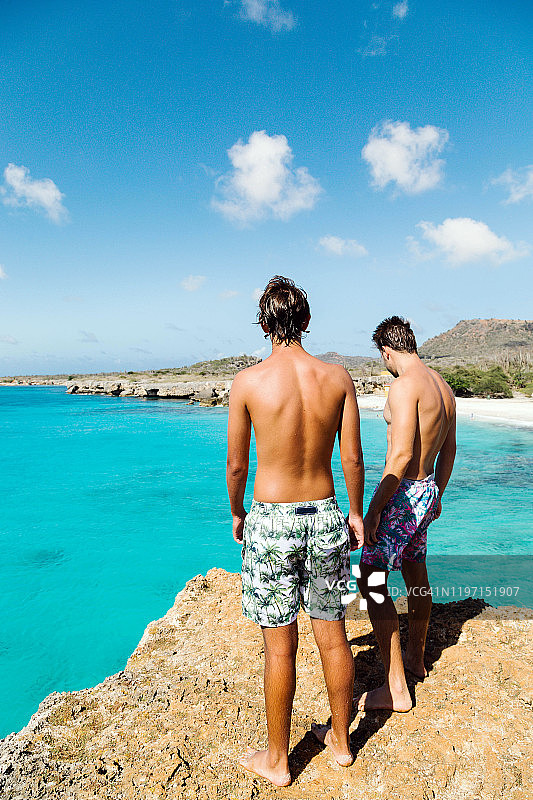 两个男孩站在蓝色加勒比海边图片素材