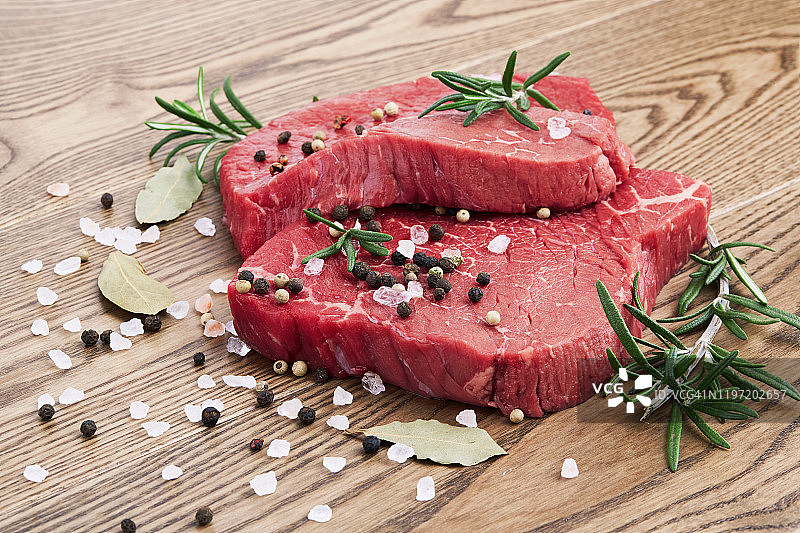 木质背景上的新鲜生肉，配迷迭香和胡椒图片素材