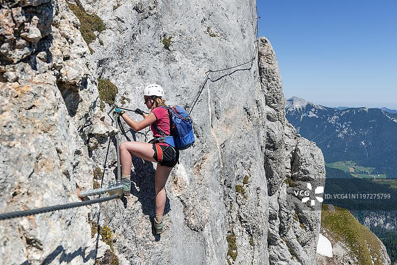 年轻女人攀登岩壁，在奥地利蒂罗尔州罗凡山脉Seekarlspitze的铁索攀岩图片素材