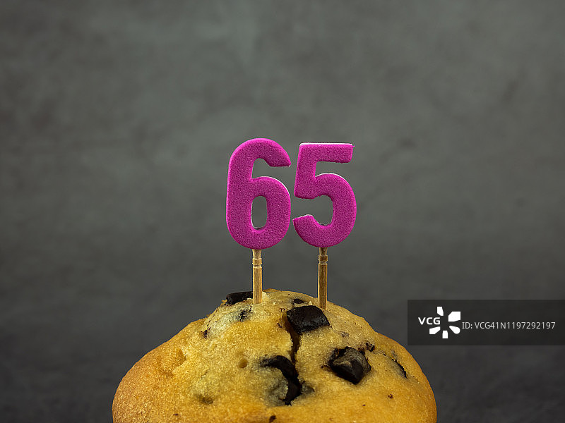 65岁生日纸杯蛋糕蜡烛，深色背景巧克力碎片图片素材
