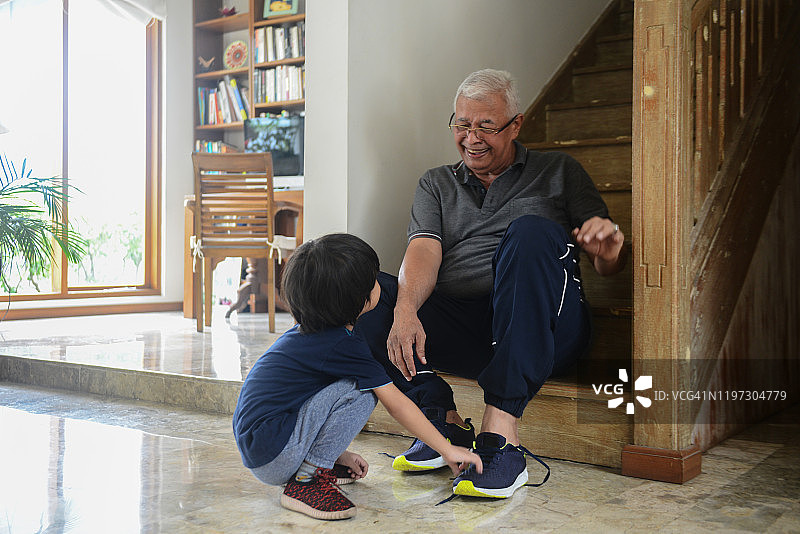 亚洲爷爷在家帮孙子系鞋带图片素材