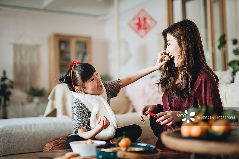 中国新年，可爱的女儿和母亲分享传统小吃，帮忙准备红包图片素材