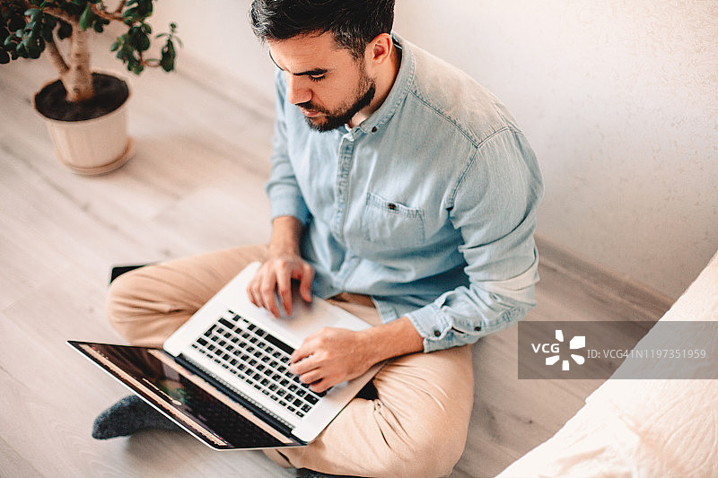 表情严肃的男人在家使用笔记本电脑图片素材