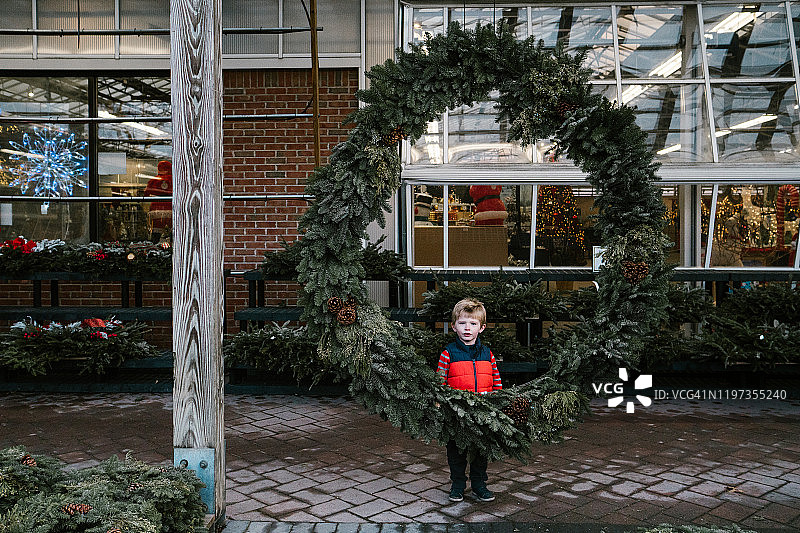 站在巨大花环后面的小男孩图片素材