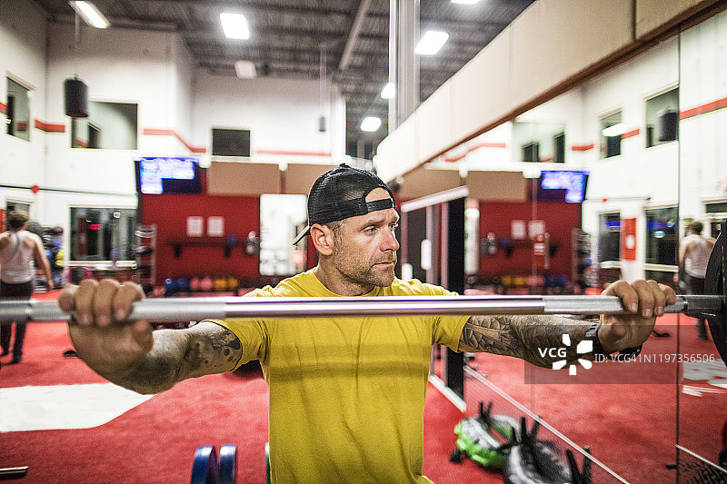 健壮男人在健身房组间休息时手持杠铃图片素材