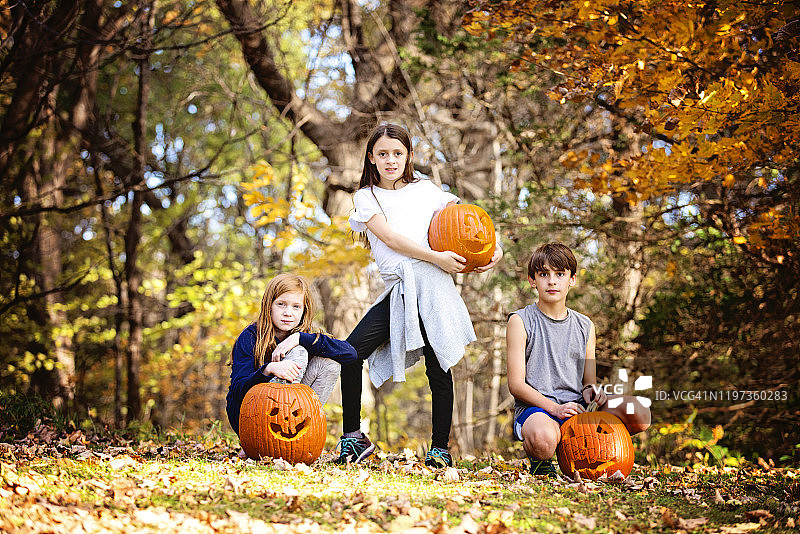 三个孩子在户外玩雕刻的南瓜图片素材