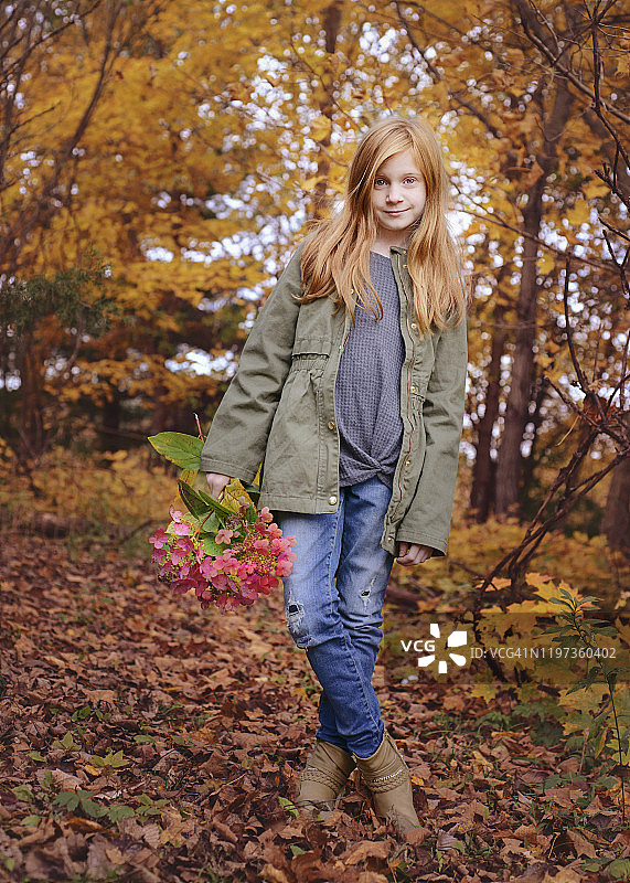秋日树林中手捧鲜花的红发女孩图片素材