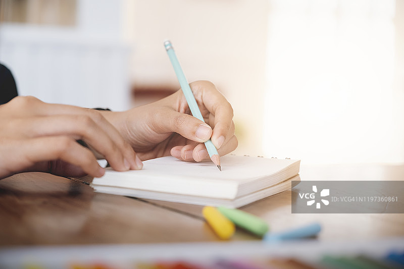 女人手握笔在笔记本上写作特写图片素材