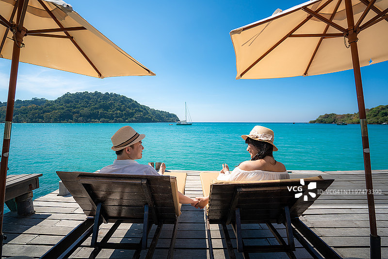 在泰国阁骨岛，亚洲幸福夫妇在海边木制平台上放松，夏天一起度假图片素材