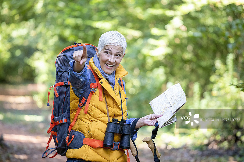 白人年长的妇女徒步森林与地形图。图片素材