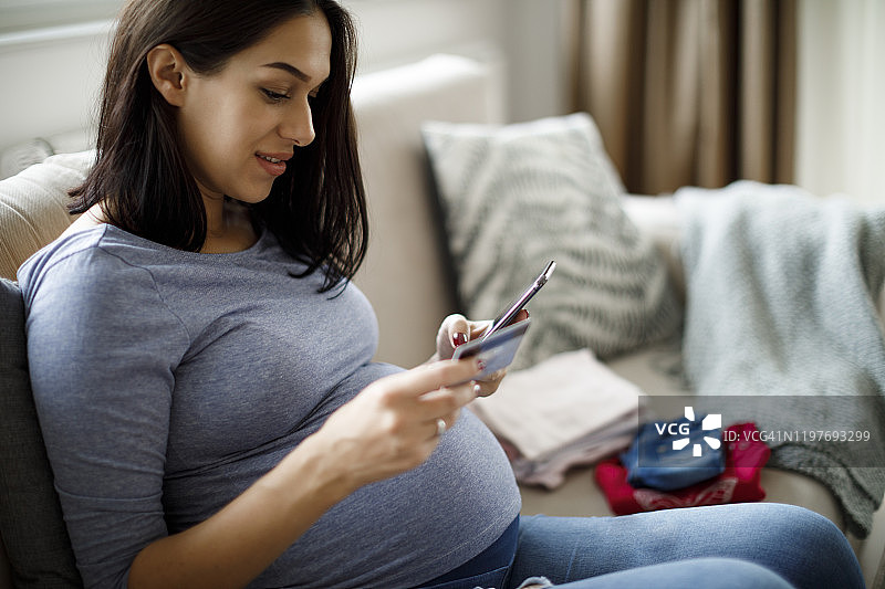 孕妇使用智能手机和信用卡在线购物图片素材