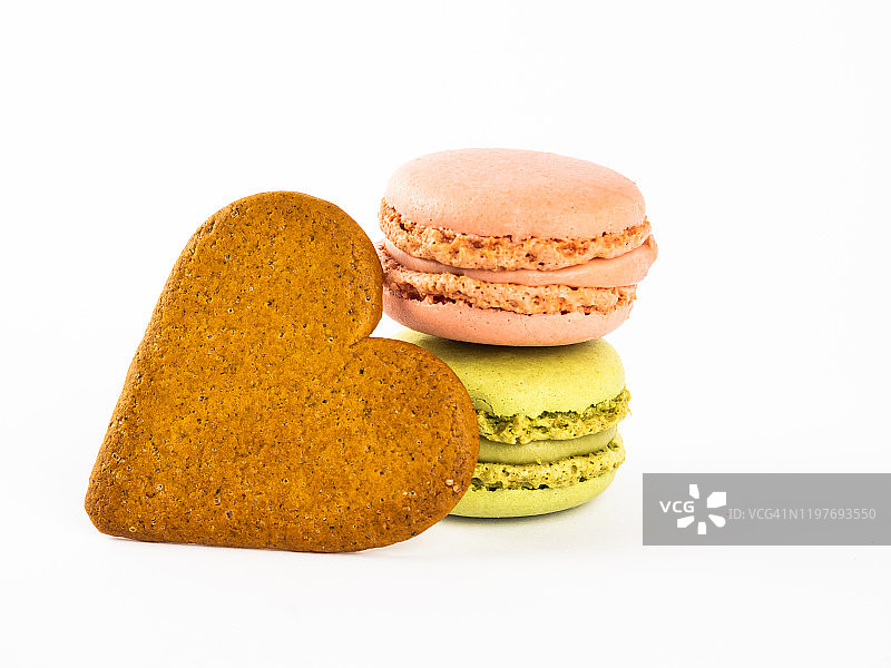 白色背景下的两颗马卡龙和心形姜饼图片素材