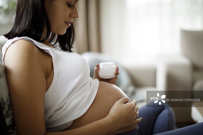 孕妇在腹部涂抹护肤霜，预防妊娠纹图片素材