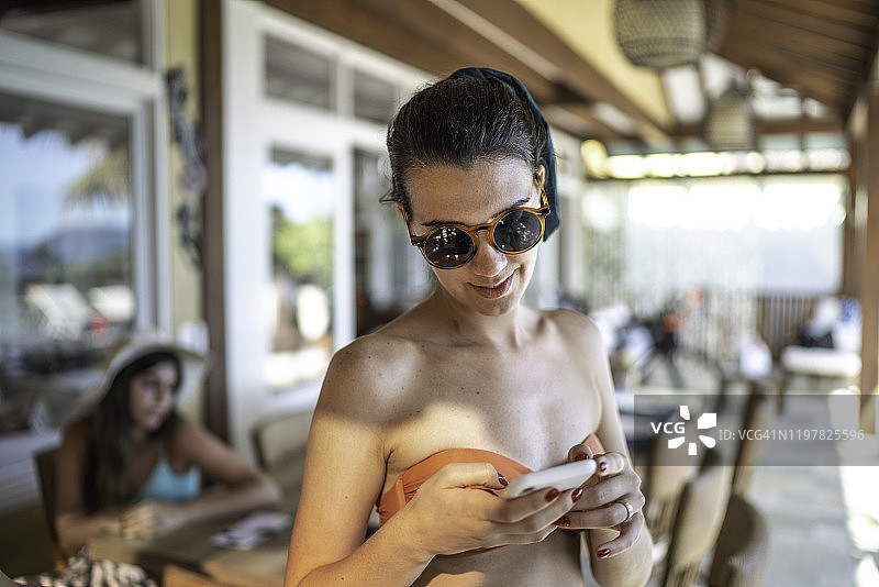 在海滩别墅使用智能手机的女性竖版照片图片素材