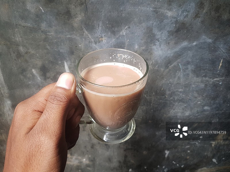 男人手拿巧克力奶站在水泥背景前图片素材
